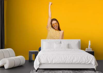 she is a winner! excited young female with laptop isolated on yellow background Wall mural