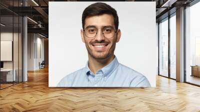 Smart businessman smiling at camera, wearing round glasses, isolated on gray background Wall mural