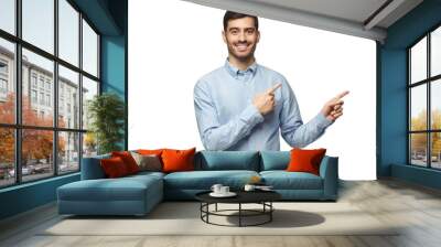 Smiling businessman pointing right with two hands and looking at camera Wall mural