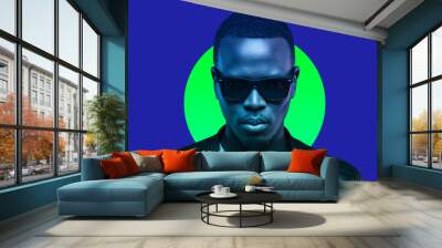 Studio portrait of african american man wearing sunglasses and leather jacket isolated on blue background Wall mural