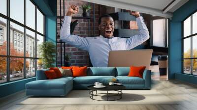 Winner. Young african american business man is very excited, celebrating in office Wall mural