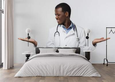 Young african doctor comparing between two options, using both hands Wall mural