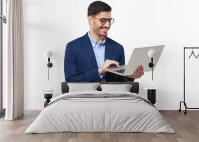 Young businessman wearing blue suit, standing with open laptop in hands, surfing the internet with smile, typing text Wall mural