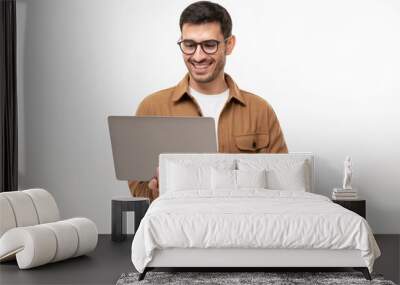 Young happy man standing with opened laptop, browsing online or typing message, isolated on gray background Wall mural