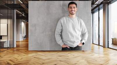 Young man in oversized sweatshirt isolated on textured gray wall background with copy space for your design Wall mural