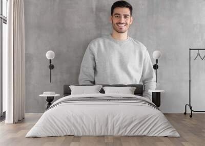 Young man in oversized sweatshirt isolated on textured gray wall background Wall mural