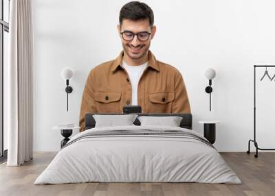 Young man looking at phone, standing isolated on gray background Wall mural