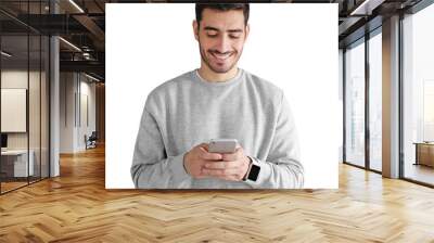 Young man standing, looking at screen of phone, browsing web and smiling Wall mural