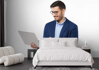 Young modern businessman wearing blue suit, standing with open laptop in hands, surfing the internet with smile Wall mural