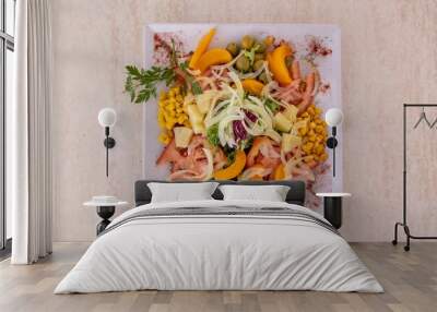 Top view of plate of delicious salad with squash, corn, and sliced ingredients on wooden table Wall mural