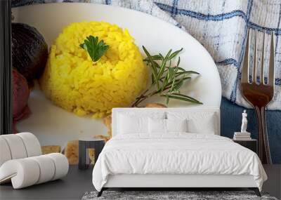 Pile of yellow rice, two onions and chicken meat on a white plate and sauce on blue table, close up Wall mural