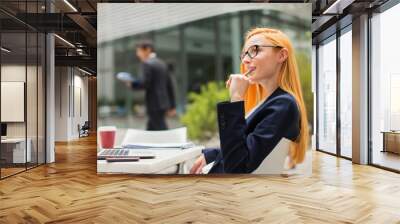 Businesswoman working at table outside of office building Wall mural