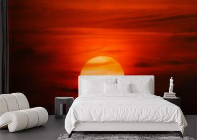 red big sun obscured by clouds near the horizon at sunset or sunrise. The sun is partially seen through the clouds  Wall mural