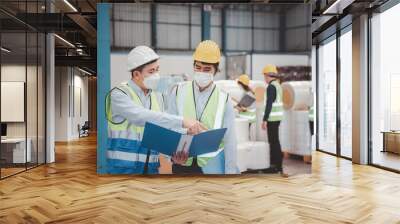 Factory manager and engineer in  medical mask and safety protective suite using computer laptop and digital tablet working discuss together Wall mural