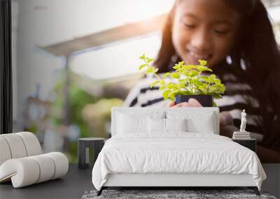 Little Asian girl hold small tree pot on hands, Environment or saving concept Wall mural