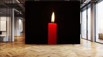 small wax burning red candle with bright flame on the dark background. Wall mural