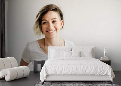 Beautiful young girl with short hair is smiling. Wall mural