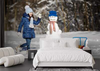 Little girl playing with a snowman Wall mural