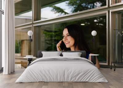 Business leadership woman talking on her smartphone with window in the background at her workplace Wall mural