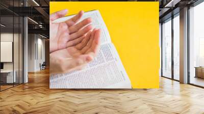 Hands on holy bible with copy space on yellow background. Wall mural