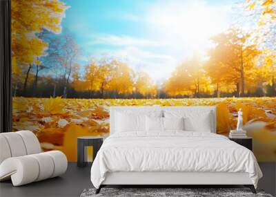 A carpet of beautiful yellow and orange fallen leaves against a blurred natural park and blue sky on a bright sunny day. Natural autumn landscape Wall mural