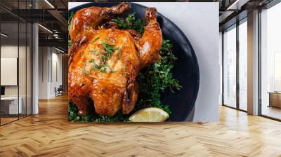 A golden roasted chicken seasoned with herbs on a tray, surrounded by fresh sprigs of rosemary, thyme, lemon slices, red and yellow bell peppers, and cherry tomatoes. Perfect for food blogs Wall mural