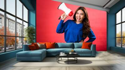 An Asian woman wearing a blue sweater is holding a red and white megaphone while speaking into it. She appears to be shouting or making an announcement. The background is solid red Wall mural