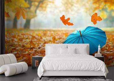 Beautiful autumn background landscape. Carpet of fallen orange autumn leaves in park and blue umbrella. Leaves fly in wind in sunlight. Concept of Golden autumn. Wall mural