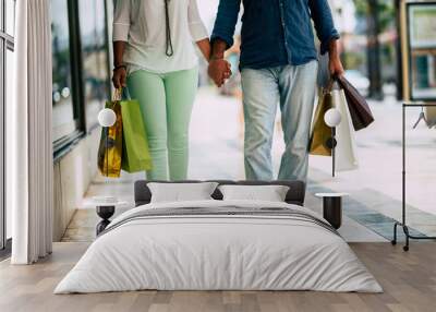 close up of legs of twoo adults walking on a mall with five shopping bags with clothes on it - relationship of man and woman together going to buy clothes Wall mural