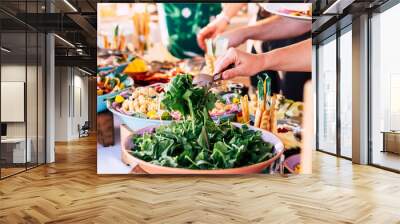 close up of view of table full of food with someone taking vegetables of the table to celebrate Wall mural