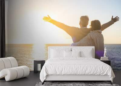 couple of two happy senior ad mature old people at the beach looking at the sea and the sun with opened arms feeling freedom. Freedom concept and lifestyle Wall mural