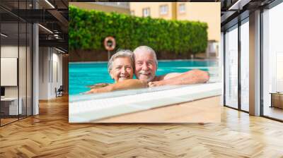 Couple of two happy seniors having fun and enjoying together in the swimming pool smiling and playing. Happy people enjoying summer outdoor in the water
 Wall mural