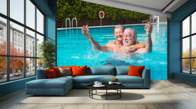 Couple of two happy seniors having fun and enjoying together in the swimming pool smiling and playing. Happy people enjoying summer outdoor in the water
 Wall mural