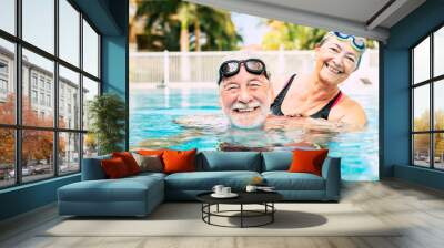 couple of two seniors hugged in the water of swimming pool - active man and woman doing exercise together at the pool - hugged with love Wall mural