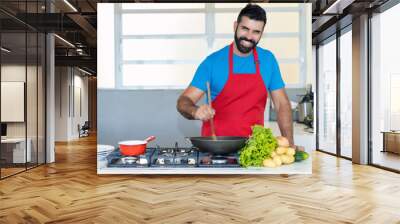 Happy laughing hispanic chef cooking at kitchen Wall mural