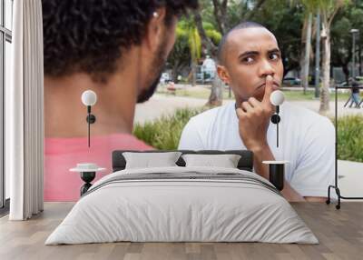 Skeptical african american man in discussion with friend Wall mural