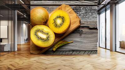 Halved ripe yellow kiwi fruit on a wooden background. Long banner format. top view Wall mural