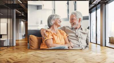 Happy laughing older married couple talking, laughing, standing in home interior together, hugging with love, enjoying close relationships, trust, support, care, feeling joy, tenderness. Wall mural