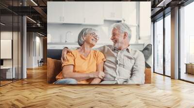 Happy laughing older married couple talking, laughing, standing in home interior together, hugging with love, enjoying close relationships, trust, support, care, feeling joy, tenderness. Wall mural