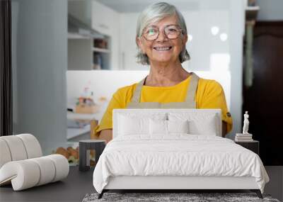 Happy senior 60s lady looking at camera, smiling. Cheerful homeowner woman, food blogger preparing ingredients for dinner. Head shot portrait preparing dinner or lunch.. Wall mural