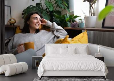 happy young woman relaxing at home with tea looking out the window. copy space. Wall mural