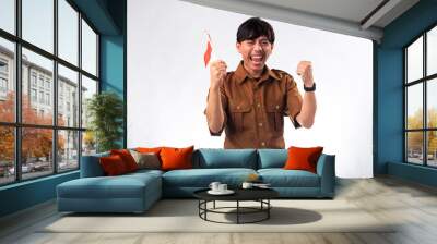 Indonesian man in a brown uniform shirt, smiling and cheering while holding an Indonesian flag. He is expressing excitement and pride, symbolizing national celebration and patriotism. Wall mural