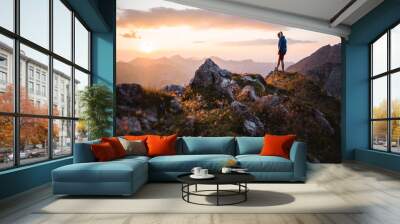 Hiker girl enjoying a sunset on top of a peak Wall mural