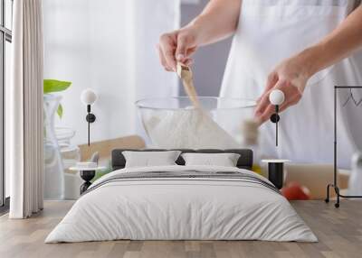 Woman adding powdered yeast to flour Wall mural