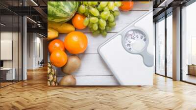 Stack of fruits and white weight scale on wooden board. Wall mural