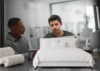 Collaborations that produce results. Shot of two young businessmen using a laptop during a meeting in a modern office. Wall mural