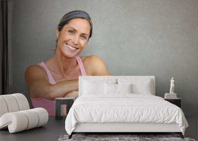 Living a healthy lifestyle. Portrait of an attractive mature woman in gymwear sitting against a gray wall. Wall mural