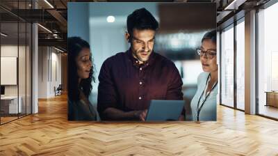 Making the late night team connection. Shot of a group of colleagues using a digital tablet together during a late night at work. Wall mural