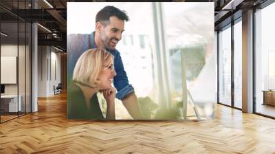 Teamwork and unity of two colleagues and coworkers working together on a computer in the office. Businessman and woman talking, discussing and planning in a meeting for brainstorming ideas at work Wall mural