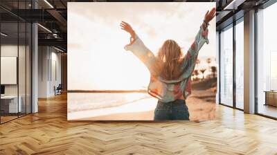 One happy beautiful woman walking on the sand of the beach enjoying and having fun at the sunset of the day. Leisure time on vacations, freedom concept. Wall mural